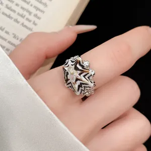 Primo piano di un anello bohémien a conchiglia con motivo zebrato sulla mano di una donna.