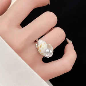 Primo piano di un anello bohémien con conchiglia e perle al dito per le vacanze.