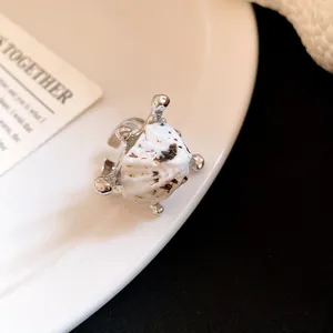 Primo piano di un anello bohémien aperto in argento con conchiglia bianca testurizzata