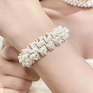 Close-up of a handmade beaded bracelet featuring white pearls and gold accents on a wrist
