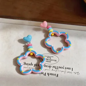 Detalle de pendientes de flores estilo dopamina con botones de corazón sobre base texturizada.