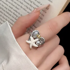 Dettaglio ravvicinato di un anello aperto bohémien a cuore con stella marina e perle