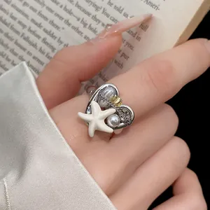 Primo piano di anello regolabile bohémien a forma di cuore con stella marina e perla
