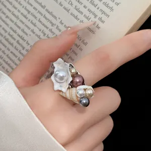 Primo piano di anello bohémien con perle colorate e conchiglie sul dito