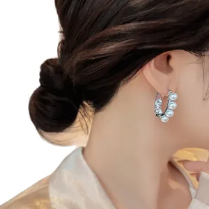 Elegant silver hoop earrings with white pearls and sparkling zircons on model
