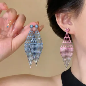 Dettaglio di eleganti orecchini a rombo traforati con strass scintillanti in rosa e argento.