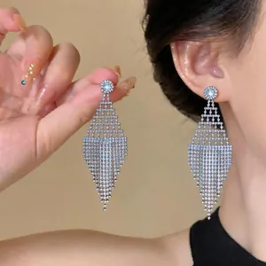 Eleganti orecchini a rombo traforato con nappe di strass mostrati all'orecchio.