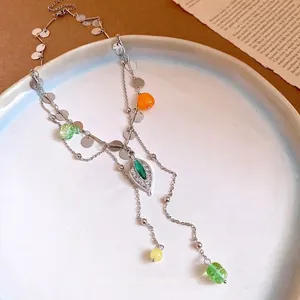 Collar de borlas con lentejuelas y colgante de hoja con diamantes en plato blanco