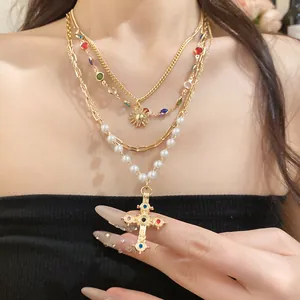 Detailansicht der goldenen Mehrschichtkette mit Perlen und verziertem Kreuzanhänger