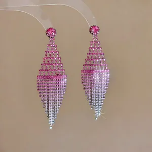 Dettaglio macro di orecchini a rombo traforati con strass rosa sfumati e riflessi luce