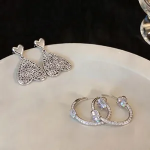 Elegante silberne Herzohrringe und Edelstein-Creolen auf einem weißen Keramikteller präsentiert