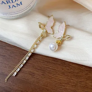 Detail shot showing intricate 14k gold plated butterfly wings and soft pearl texture.