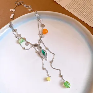 Detalle de collar de borlas con hoja de plata, cuentas de vidrio de colores y lentejuelas