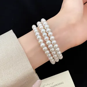 Detailansicht eines eleganten dreireihigen Perlenarmbands am Handgelenk für einen Vintage-Look.