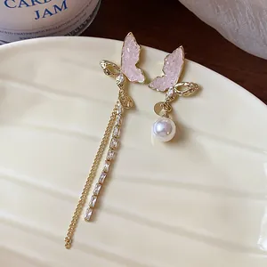 Close-up of elegant asymmetric butterfly earrings with pearls and gold-plated tassels.