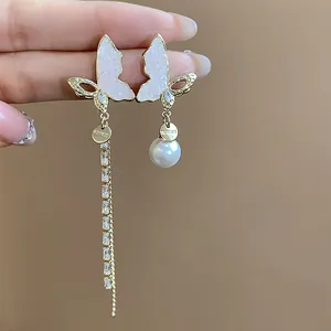 Detailed view of 14k gold-plated asymmetrical butterfly earrings with pearls