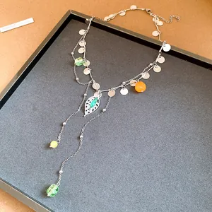 Primer plano de collar plateado con lentejuelas, colgante de hoja y cuentas de colores