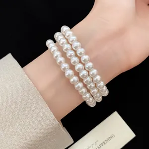 Nahaufnahme eines eleganten dreireihigen Perlenarmbands am Handgelenk, Vintage-Stil.