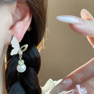 Close-up of elegant 14k gold plated butterfly earring with a white pearl drop.