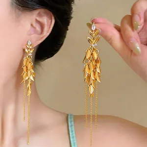 Detailansicht goldener Weizenähren-Ohrringe mit langen Quasten und Zirkonia am Ohr.
