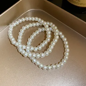 Nahaufnahme von drei eleganten weißen Perlenarmbändern im Vintage-Stil auf einem Goldtablett
