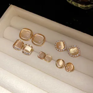 Detailed close-up showing diverse gold-toned cat's eye stone earrings in a velvet tray