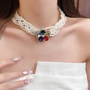 Detailansicht eines mehrreihigen Perlen-Chokers mit einem farbenfrohen Edelstein-Blumenanhänger.