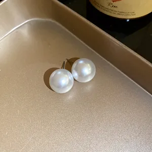 Detailansicht eleganter großer weißer Perlenohrstecker auf einem goldenen Tablett