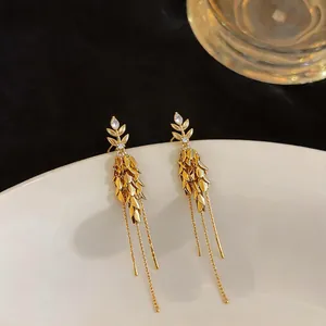 Detailaufnahme eleganter goldener Quastenohrringe mit funkelndem Zirkon-Ähren-Design
