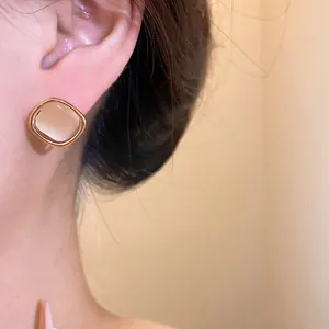Close-up of elegant square cat's eye stud earring with gold border on model's ear