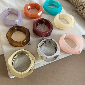 Primo piano di grossi bracciali in resina irregolari in vivaci colori caramella e metallo