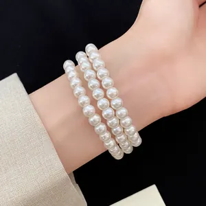 Detailaufnahme eines eleganten dreireihigen weißen Perlenarmbands an einem Handgelenk
