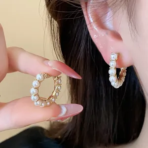 Close-up detail of 14k gold plated hoop earrings with elegant white pearls design