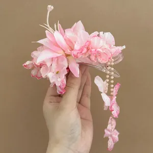 Detailed macro view of a pink fabric flower hair clip featuring elegant tassel beads