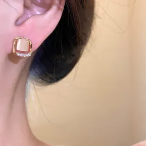Detailed macro shot of a golden square stud earring featuring cat's eye stone and diamonds