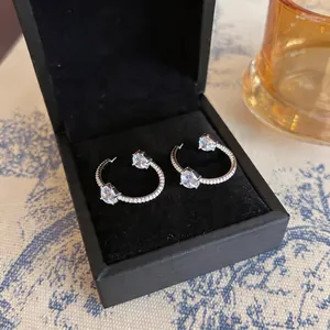 Detailansicht eleganter Silberohrringe mit Herzsteinen in einer schwarzen Geschenkbox