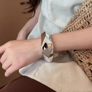 Primo piano di un bracciale rigido largo irregolare argento con sfaccettature geometriche
