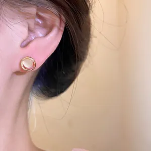 Detailed view of elegant circular gold cat's eye stone stud earring worn on the ear