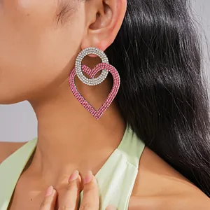Vista detallada de pendientes de corazón extragrandes con pedrería en una modelo