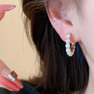 Detailed close-up showing elegant 14k gold plated pearl hoop earrings worn on an ear