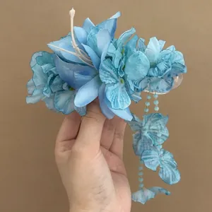 Detail view of light blue fabric flower hair clip with elegant hanging bead tassels