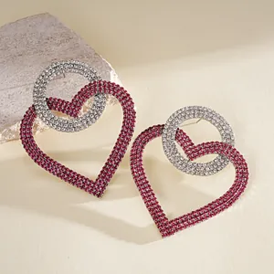 Detalle en primer plano de pendientes de corazón con pedrería rosa sobre piedra texturizada.