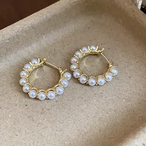 Detailed view of 14k gold plated pearl hoop earrings in a professional display tray