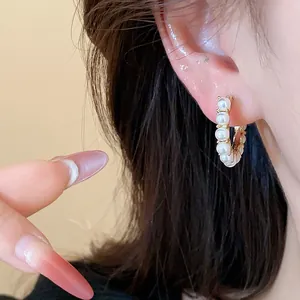 Close-up view of elegant 14k gold plated hoop earrings with white pearls on ear