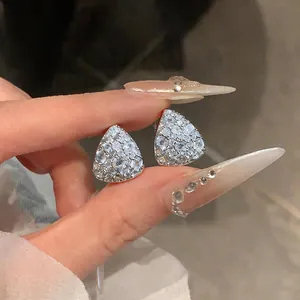 Dettaglio ravvicinato di orecchini a lobo a goccia in argento con zirconi brillanti.
