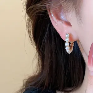 Macro close-up view of 14k gold plated pearl hoop earrings in a French chic style