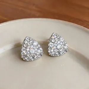 Primo piano di orecchini a lobo triangolari color argento con zirconi cubici chiari