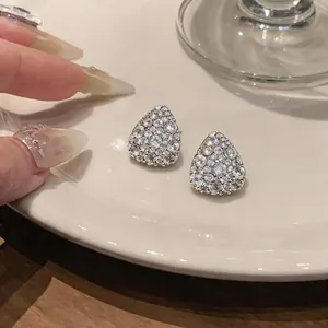 Primo piano di eleganti orecchini a bottone in argento a goccia con zirconi pavé.