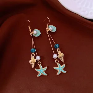 Detailed view of nautical bohemian drop earrings with teal starfish, golden shells and pearls
