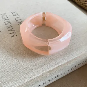 Dettaglio di un bracciale rigido largo e irregolare in resina pesca su un libro